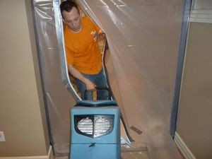 Water Damage Restoration Technician Using Air Mover Near Vapor Barrier